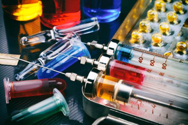 istock Syringes with medication on sterilization box, ampoules and vials with fluid on glossy surface. Toned 898968526