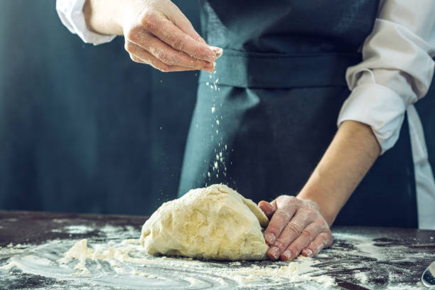 istock The chef in black apron makes pizza dough with your hands on the table 898971000