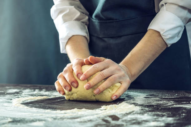 istock The chef in black apron makes pizza dough with your hands on the table 898971042