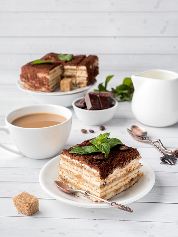 Tiramisu Dessert with Mint and Cup of Coffee on White Wooden Table.