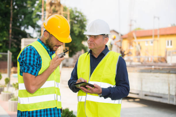 istock Workers in hardhat and green jacket posing on building site 898976256