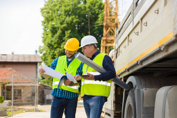 istock Workers in hardhat and green jacket posing on building site 898976494