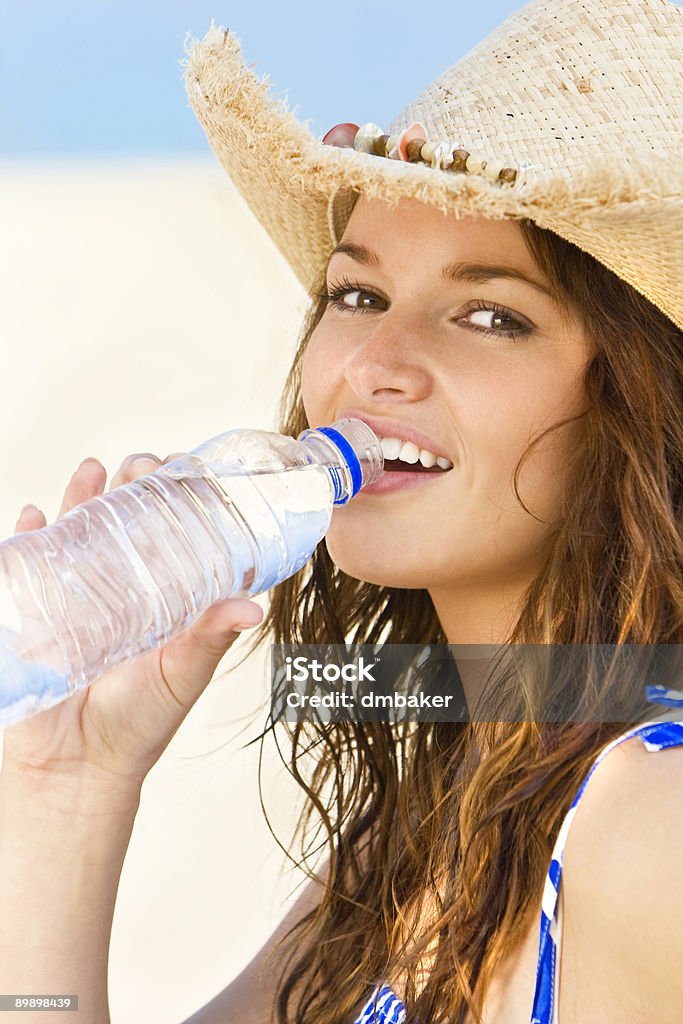 Сексуальная женщина в Ковбойская шляпа питьевой прохладную воду на пляже - Стоковые фото 20-29 лет роялти-фри
