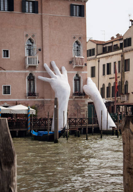 View of a monumental installation sculpture (called support) by Italian artist Lorenzo Quinn for the 2017 Venice Art Biennale to raise awareness about global warming in Venice. View of a monumental installation sculpture (called support) by Italian artist Lorenzo Quinn for the 2017 Venice Art Biennale to raise awareness about global warming in Venice. venice biennale stock pictures, royalty-free photos & images