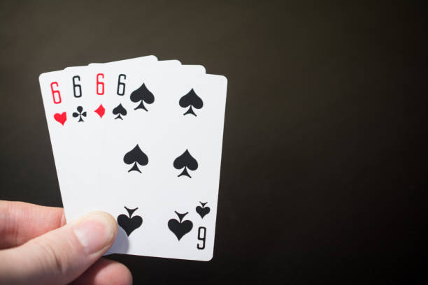 istock Abstract: man hand holding playing card four six isolated on black background with copyspace poker set four six 898998046