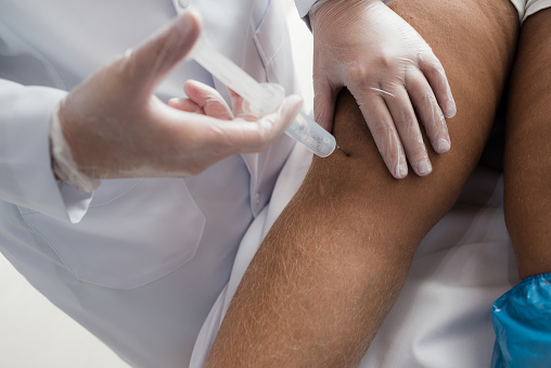 Therapist applying ozone injection to patient's knee.