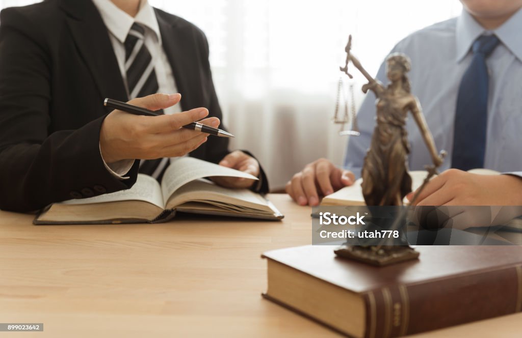 lawyer and client Law, Legal advice, Legislation concept. Lady justice on law book with lawyer and client in law office. Law Stock Photo
