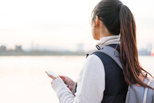 istock woman standing by riverside using phone 899028736