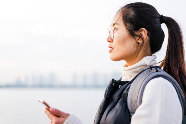 woman standing by riverside using phone