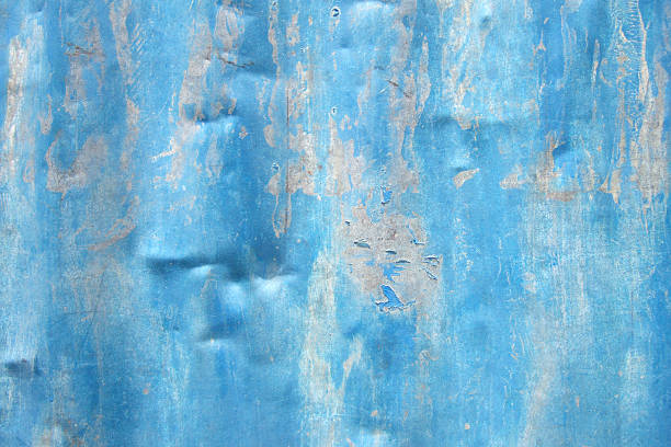 Dented tin sheet with peeling blue paint stock photo
