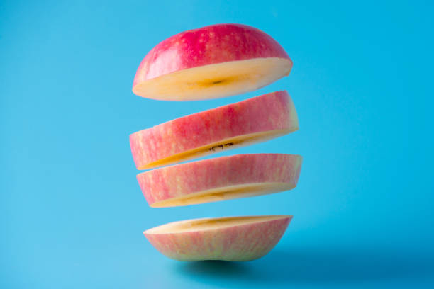 istock Red ripe Apple cut slices in the air on blue background 899043582