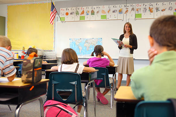 African American teacher talking to elementary students on a class in the classroom.