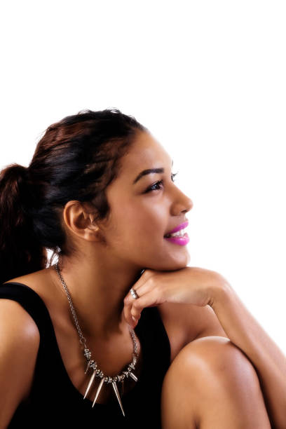 Young lady poses for this close-up portrait. She is turning her head to the side where the camera is to look over her right shoulder. She is latin, with brown eyes and hair. Her hair is brown, long and smooth. She looks like in her twenties.