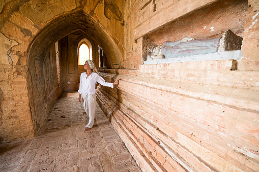 Caucasian young woman contemplating the Bagan ancient temple from inside. People travel concept.