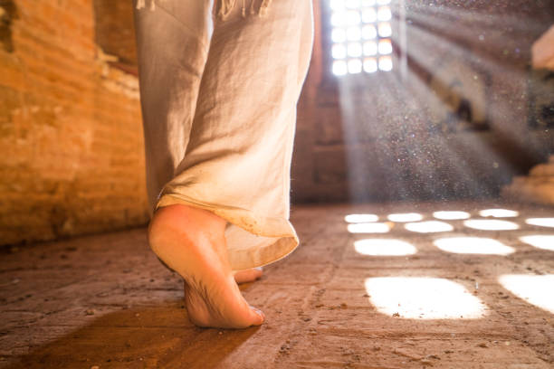 Young woman walking inside ancient temple in the Bagan archeological zone at sunrise, close up on barefoot, sunlight coming through window. People travel concept.