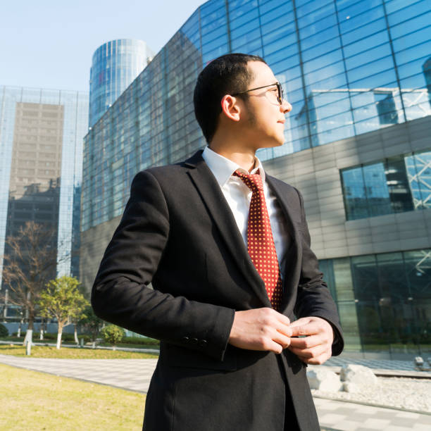 istock young businessman buttoning black suit,looking away 899056594