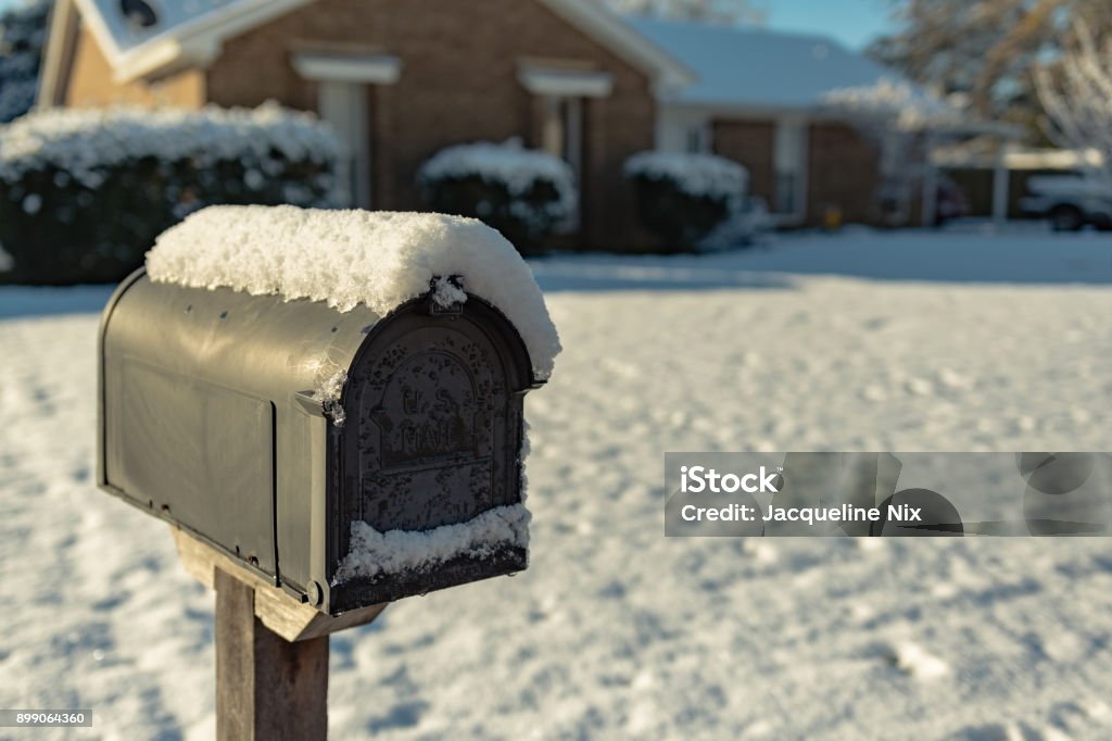 snow-covered mailbox Snow-covered black mailbox with snow-covered house and yard out of focus in backgroung Snow Stock Photo