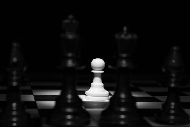 istock White pawn standing alone in spotlight on chess board between black pieces artistic conversion 899065120