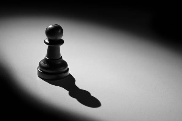 istock Chess pawn standing in a spotlight that make a shadow with darkness 899065376