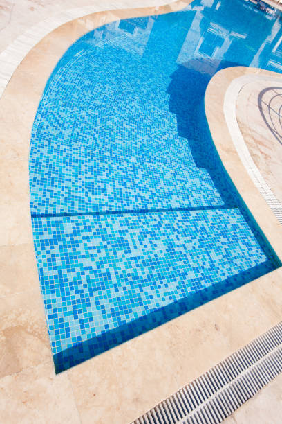 istock Blue swimming pool with teak wood flooring 899068926