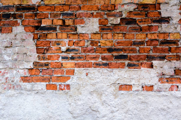 istock Ancient brick wall with plaster made of red-orange brick. Shattered surface. An abandoned house or an old factory. 899071094