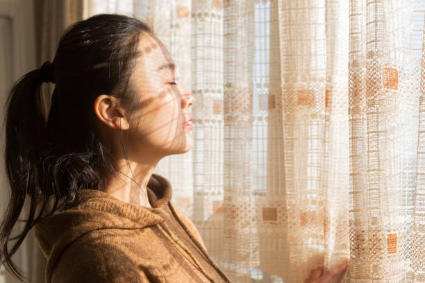 istock woman standing at window with eyes closed 899071400
