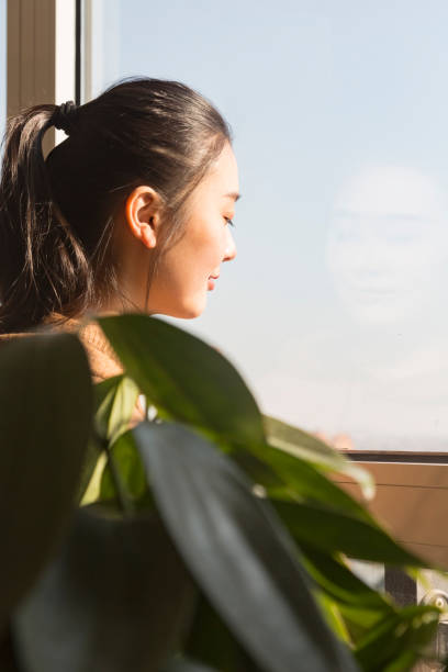 istock woman standing at window with eyes closed 899071424