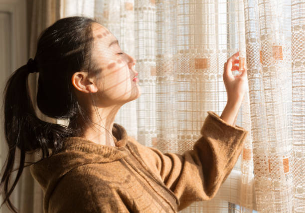 istock woman standing at window with eyes closed 899073544