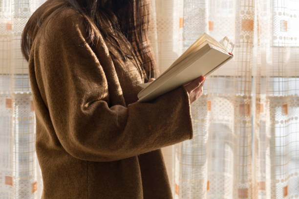 istock woman reading book by home window 899073992
