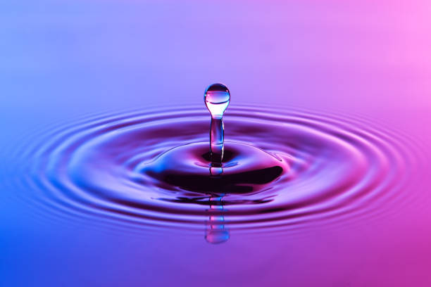 istock Water drop close up with concentric ripples on colourful blue and pink surface 899074854