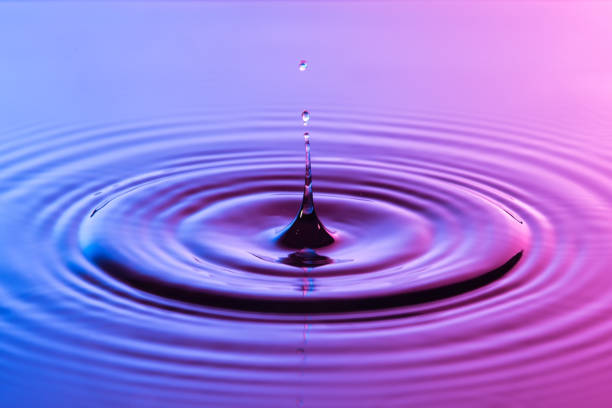 istock Water drop close up with concentric ripples on colourful blue and pink surface 899075008