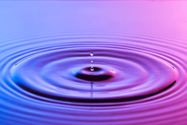 istock Water drop close up with concentric ripples on colourful blue and pink surface 899075048