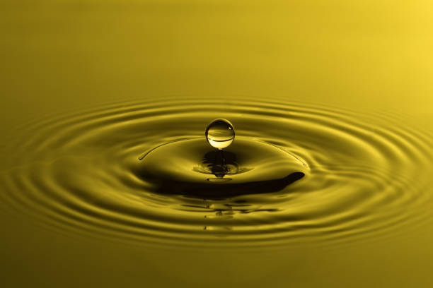 Water drop close up with concentric ripples on colourful yellow surface