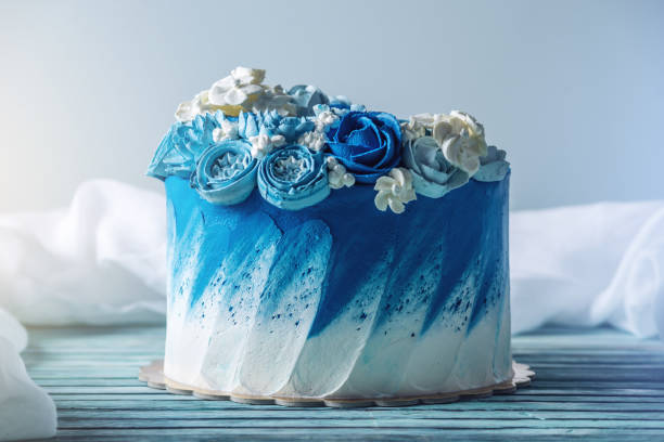 красивый синий свадебный торт, украшенный белыми цветами сливок. концепция праздничных десертов на день рождения - white icing стоковые фото и изображения