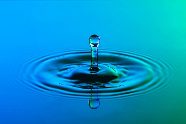 istock Water drop close up with concentric ripples on colourful blue and green surface 899077684