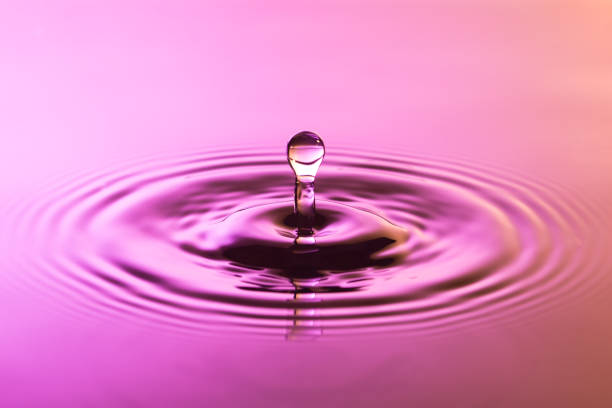 istock Water drop close up with concentric ripples on colourful pink and yellow surface 899077688