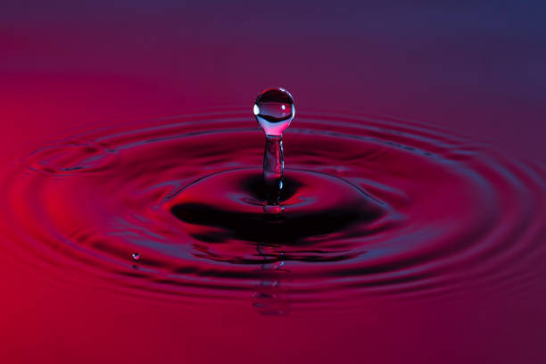 istock Water drop close up with concentric ripples on colourful blue and red surface 899078110