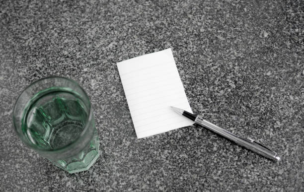 Empty paper note with pen and glass of water
