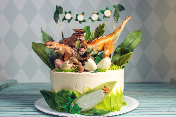 Children's holiday white cake decorated with dinosaurs in the Jurassic period jungle. Concept ideas desserts for kids stock photo