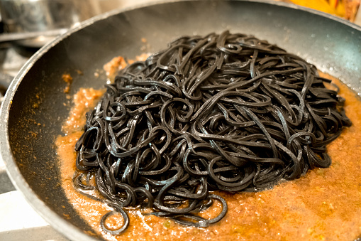 black pasta squid ink in a pan - italian taglierini al nero di seppia recipe