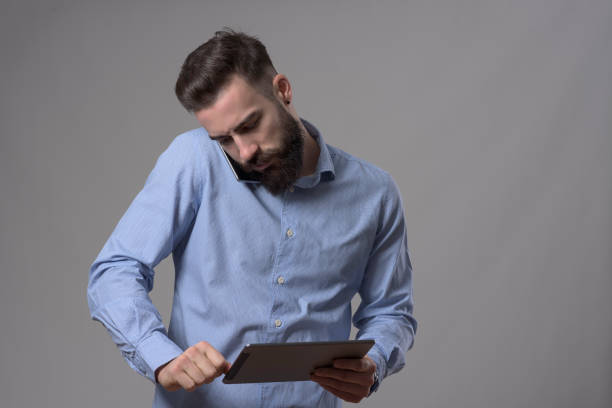 istock Young business man holding mobile phone on shoulder talking and looking at tablet computer 899095994
