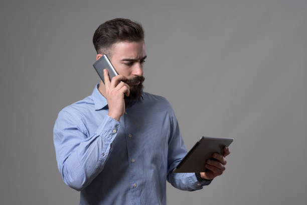 istock Serious confident young business man talking on the phone and looking at tablet computer 899096136