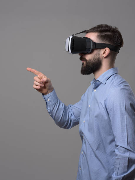 istock Profile view of young business man with vr headset touching interactive augmented reality touch screen with finger 899099350