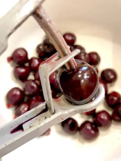 Summer Christmas: preparing food by removing stones (pips) from cherries: pitting