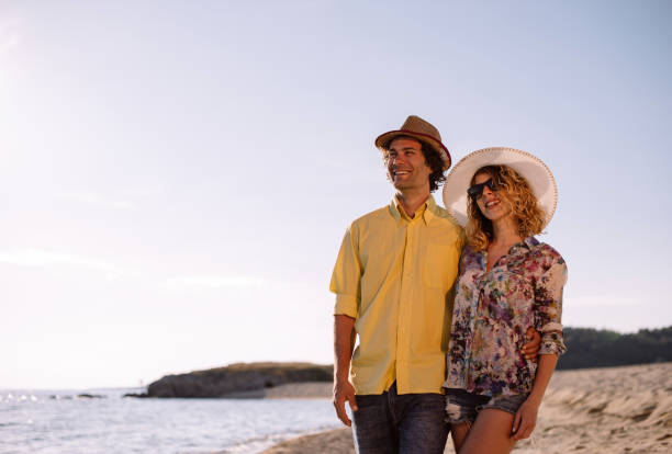 istock Young couple walking on the beach with straw hats 899111892