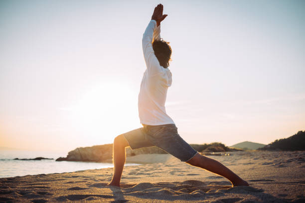 Warrior pose on the beach in sunset Use your holiday and practice yoga every day at the beach, during the day or in the sunset. Yoga enthusiast is practicing yoga in sunset at the beach in Greece warrior position stock pictures, royalty-free photos & images