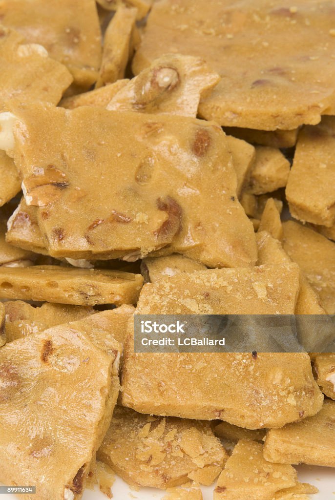 Macro photograph of fresh homemade crunchy peanut brittle candy Macro photograph of freshly made crunchy and very sticky peanut brittle candy. Details show the peanuts in the broken pieces. Peanut brittle is best served in pieces.  Broken Stock Photo