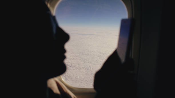 istock Closeup silhouette woman sitting near airplane window using mobile phone during flight 899117274