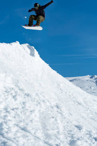 istock Snowboarder jumping against blue sky 899117584
