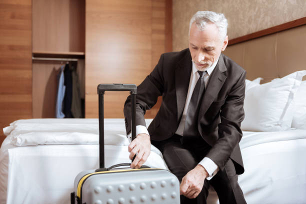 istock Senior focused man  locking luggage 899121892